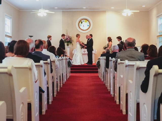 A couple saying their vows, holding hands at the front of the Universalist Unitarian Church of Farmington.