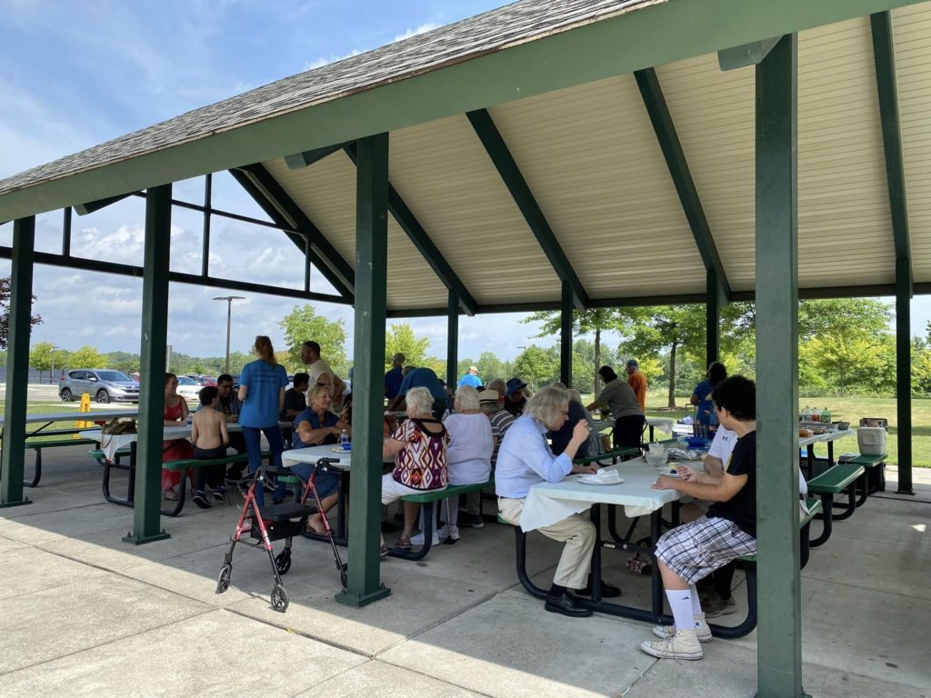People sitting at picnic tables under a pavilion