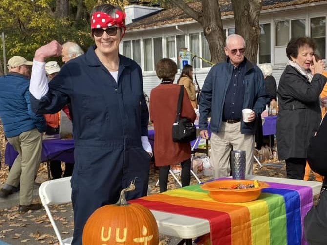 Multiple people standing near event table with Pride flag displayed.