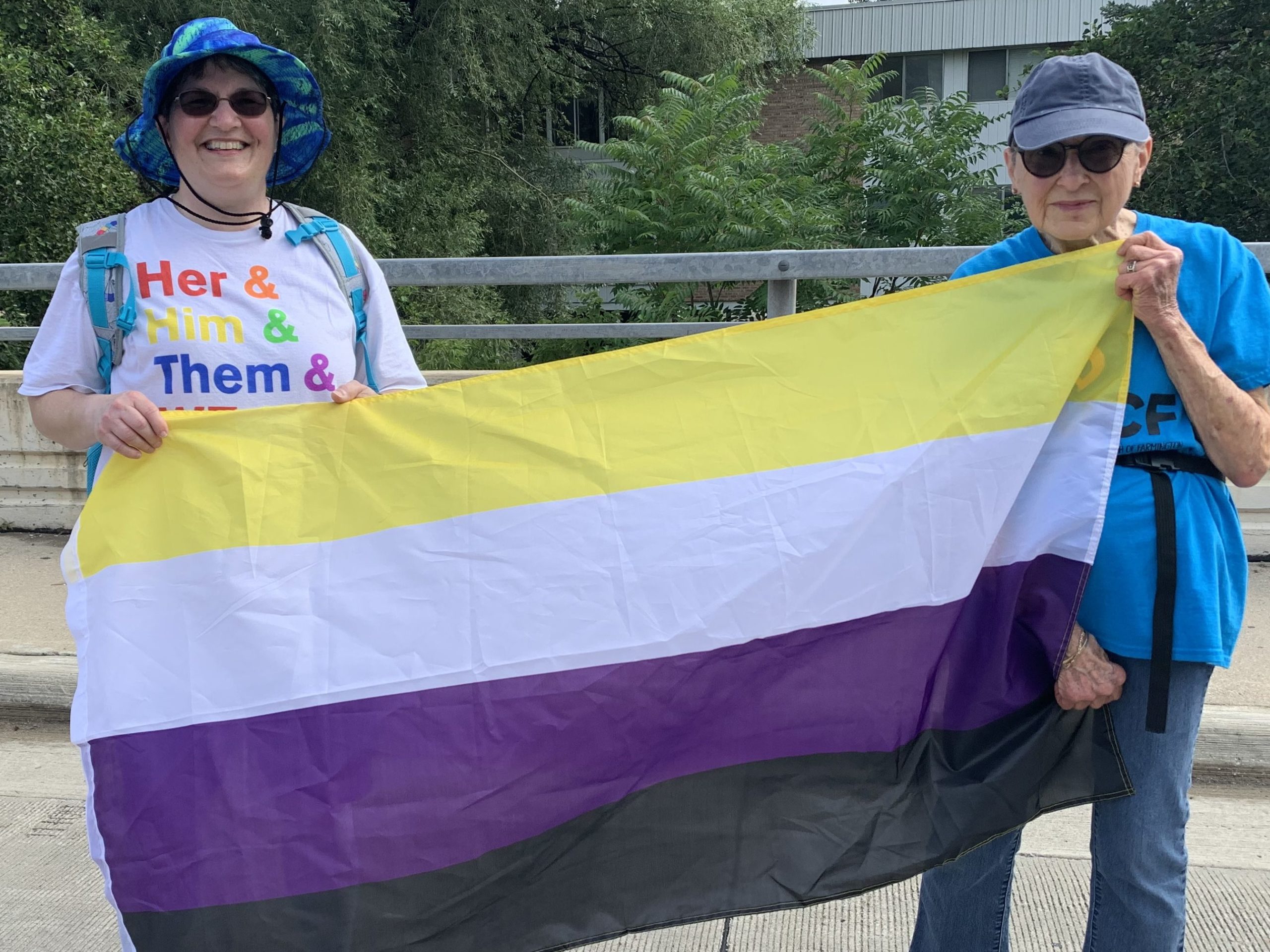 Two people carrying the nonbinary flag